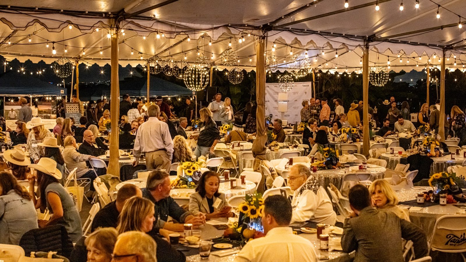 Guests gathered under a dinner tent at the Harvest Moon benefit