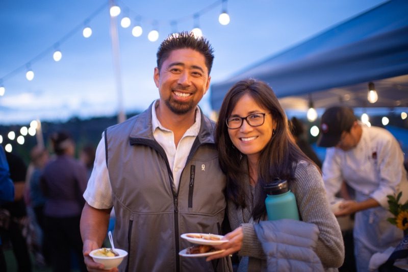 A smiling couple enjoying the evening under string lights at Harvest Moon