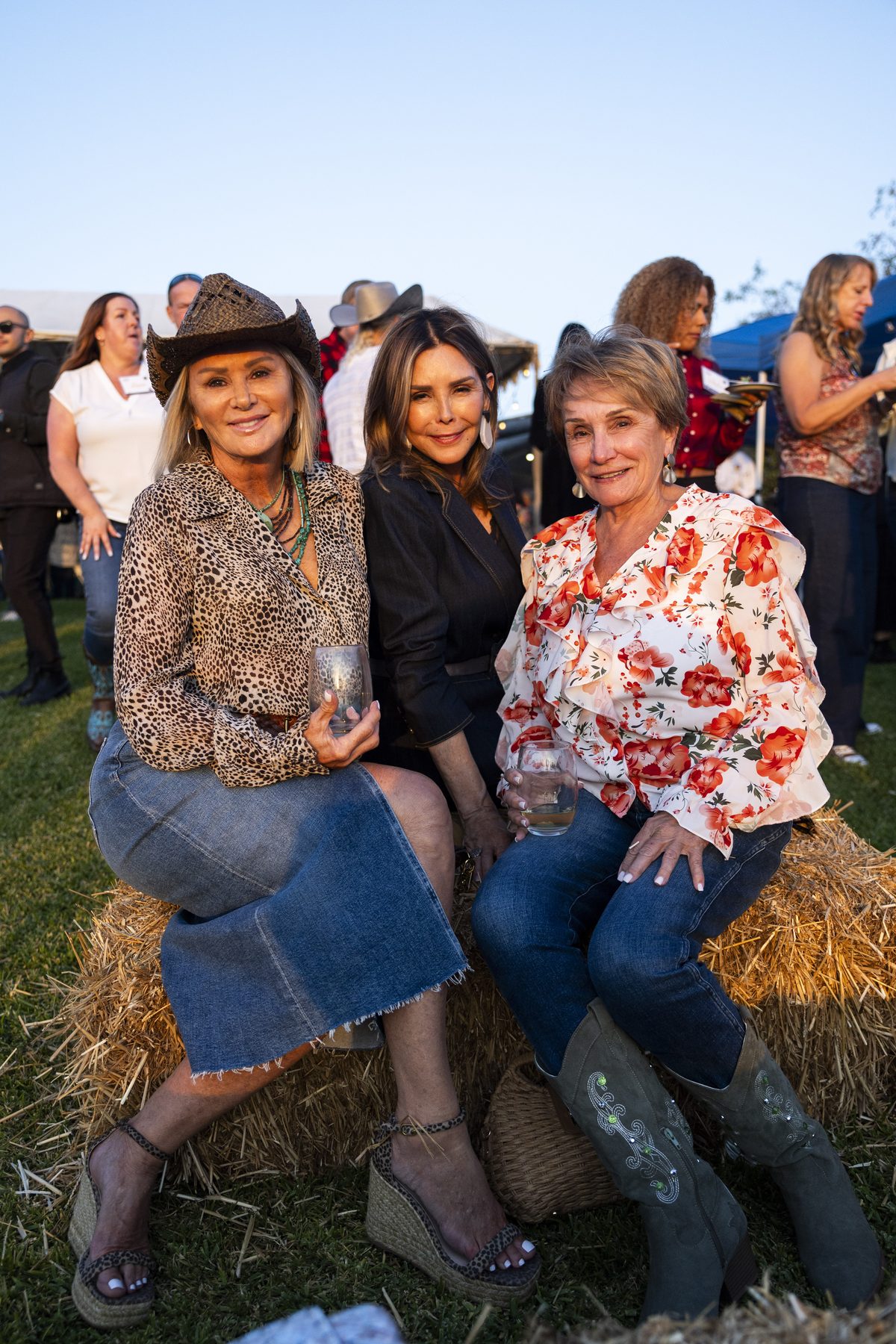 Three guests seated on hay bales at the Harvest Moon dinner