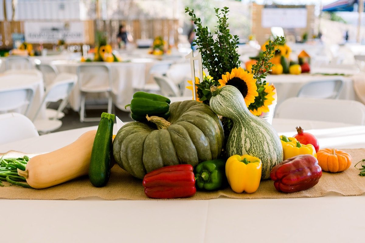 Harvest produce and sunflower centerpiece with tent tables stretching behind