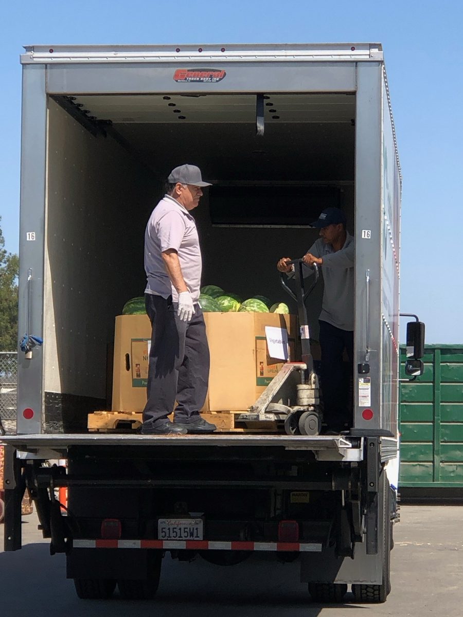 Workers loading pallets of watermelons onto an OCFB distribution truck